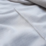 Imagem em close de uma camisa branca com zíper, mostrando as pences que realçam a modelagem da peça.